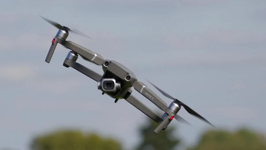 Сірий квадрокоптер Mavic 2 летить у повітрі на тлі неба